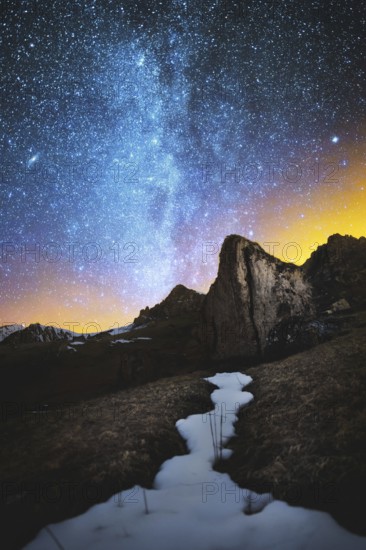 Night scenery done on long exposure. A beautiful Caucasian landscape of red rocks against the background of the cold milky way and a warm yellowish red glow on the horizon behind the rocks. The concept of beautiful Caucasian nature in the bright colors o