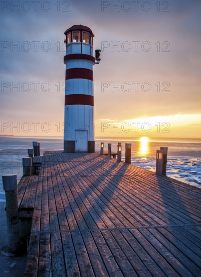 Winter landscape with lighthouse on a lake at sunset