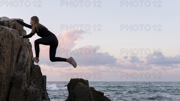 Side view woman climbing coast