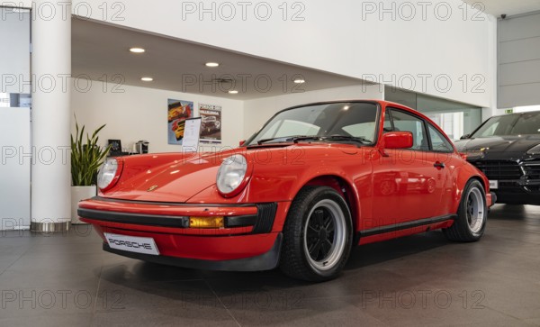 A picture of a red Porsche 911 Carrera 3.0 inside a dealership