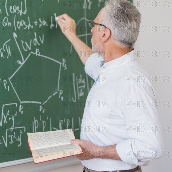 Serious lecturer glasses chalking formula blackboard