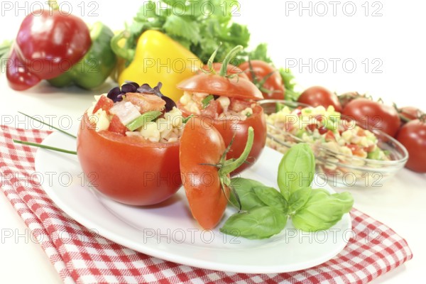 Stuffed tomatoes with pasta salad and peppers on a light-coloured background