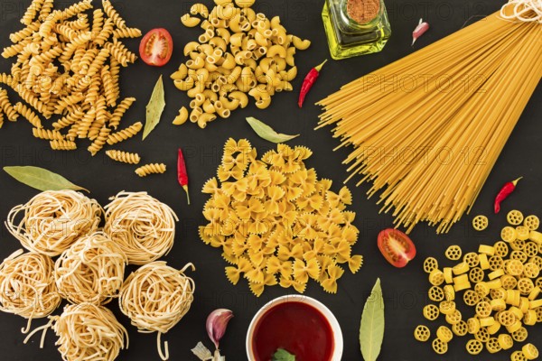 Different type raw pasta with ingredients black background