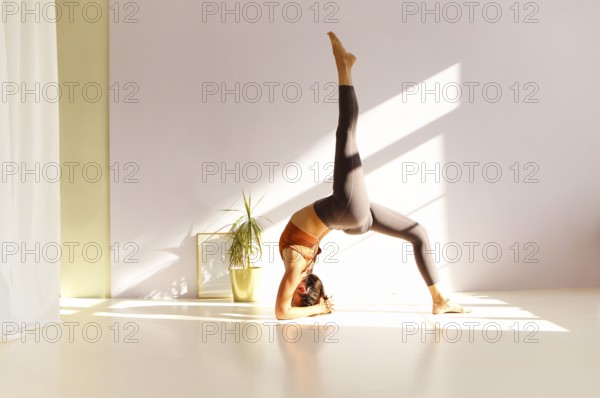 Side view of calm female in sportswear practicing yoga in Firefly pose while balancing on arms on mat and looking away