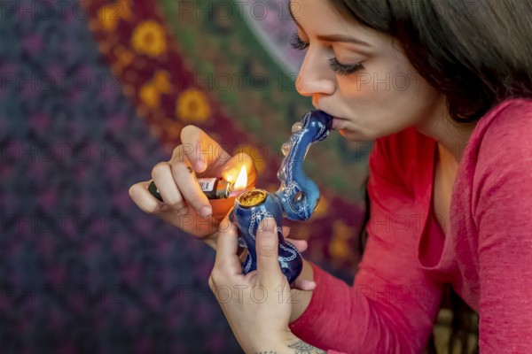 A beautiful brunette model smokes marijuana in the privacy of her own home