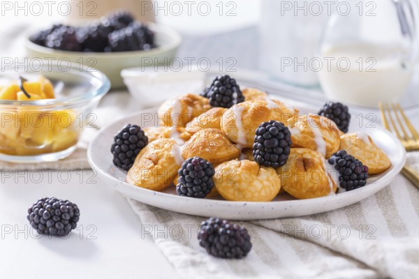 Dutch mini pancakes called poffertjes with blackberries and apple compot