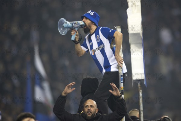 Football match, a fan of FC Porto with jersey on the fence shouting with a megaphone, another fan of FC Porto below with raised arms and in a cheering mood, football stadium Estadio do Dragao, Porto, Portugal, Europe