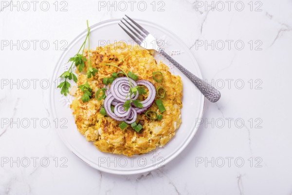 Tortilla - spanish omelet with potatoes, onions and herbs on white background