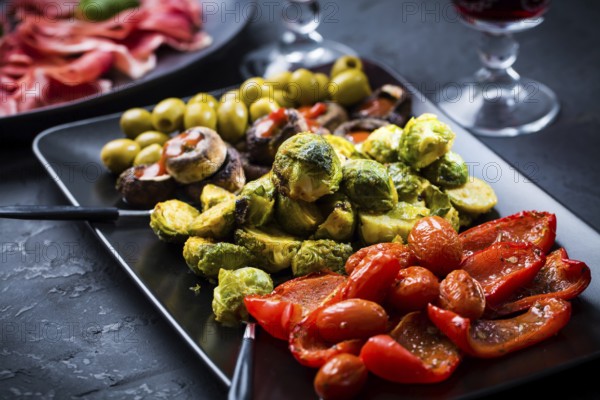 Assortment of appetizers and tapas with red wine on black background