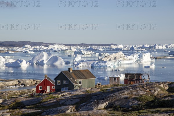 Rodebay, Greenland, July 09, 2018: Colorful wooden houses with icebergs in the background. Rodebay, also known as Oqaatsut is a fishing settlement north of Ilulissat, North America