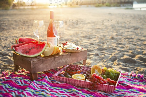 Outdoor picnic with rose wine, fruits, nuts meat and cheese