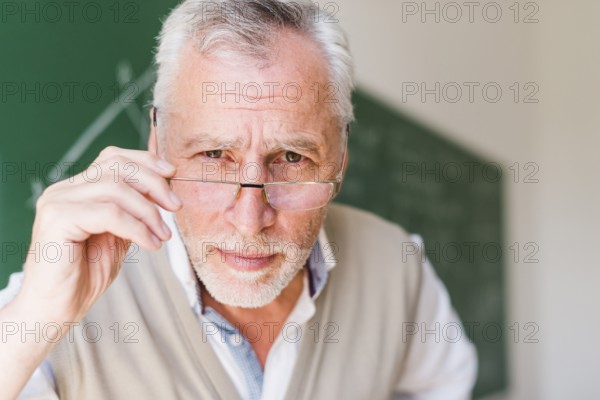 Senior professor putting glasses classroom