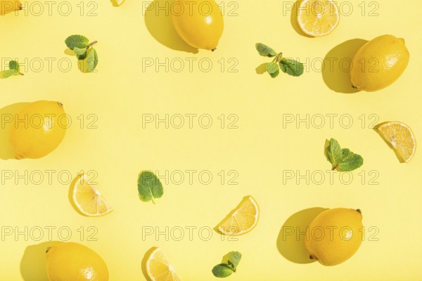 Fresh yellow lemons with mint on minimal beige yellow background on bright sun light with hard shadows pattern summer background flat lay from above, citrus food composition, space for text