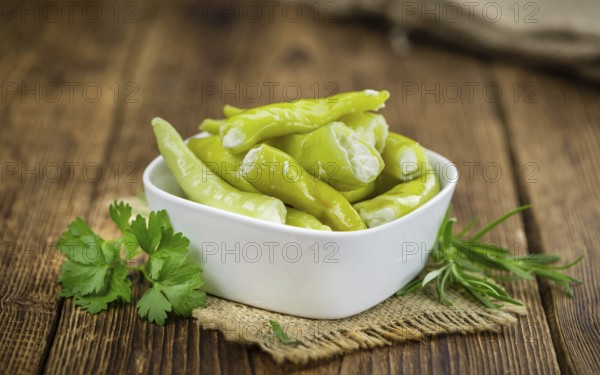 Fresh made Green Chilis (filled with cheese) on an old and rustic wooden table (selective focus, close-up shot)