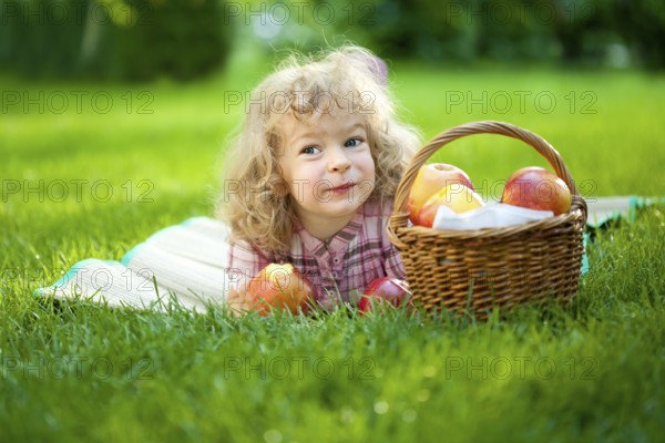 Happy smiling child eating apple outdoors in spring park