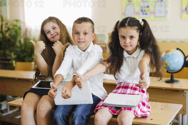 Children sitting school desk gesturing