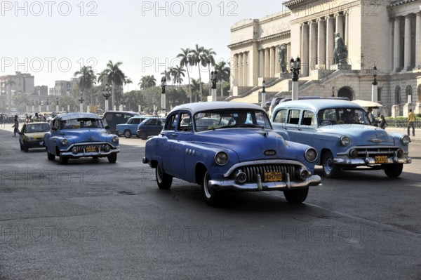Row of vintage cars driving on a wide city street, Havana, Cuba, Central America