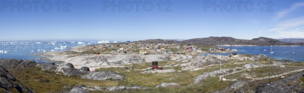 Rodebay, Greenland, July 09, 2018: Colorful wooden houses with icebergs in the background. Rodebay, also known as Oqaatsut is a fishing settlement north of Ilulissat, North America