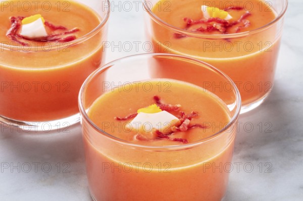 Salmorejo, Spanish cold tomato and bread soup, in glasses on a marble background, close-up shot