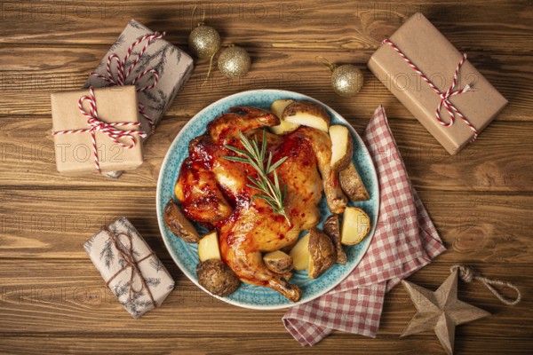 Festive Christmas dinner with roasted whole chicken top view on wooden rustic background with Xmas toys and wrapped presents, festive table composition flat lay
