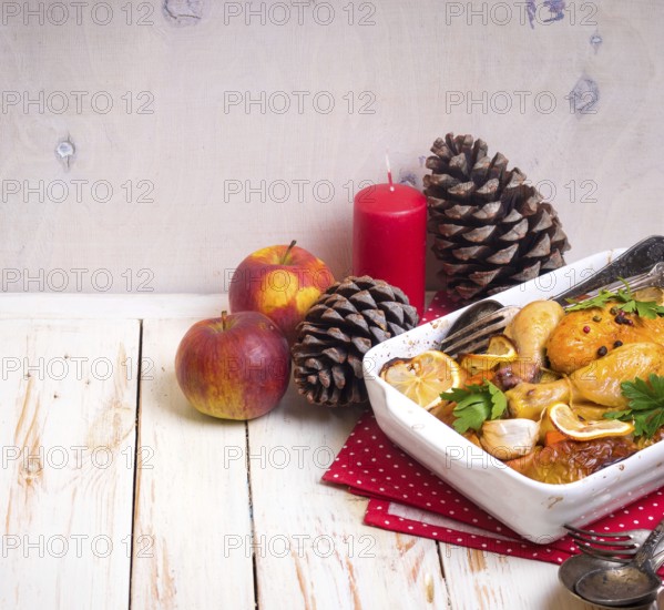 Roasted chicken. Christmas food. Celebration white wooden table with roasted chicken, apples, decorated with candles, cones, vintage cutlery. Christmas/Thanksgiving dinner. Festive table