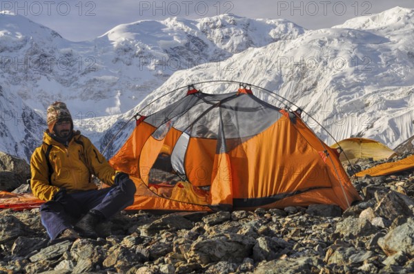 Adventurous hiker camping near Engilchek glacier in scenic Tian Shan mountain range in Kyrgyzstan