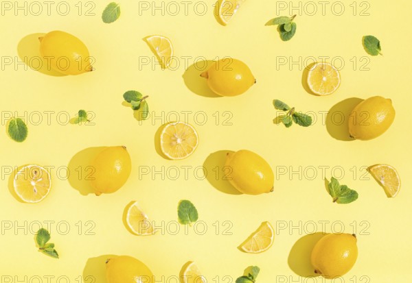 Fresh yellow lemons with mint on minimal beige yellow background on bright sun light with hard shadows pattern summer background flat lay from above, citrus food composition, space for text