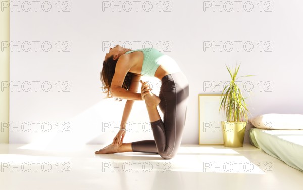 Side view of calm female in sportswear practicing yoga in Firefly pose while balancing on arms on mat and looking away