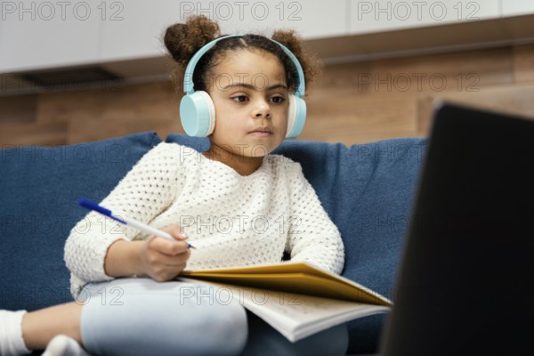 Little girl during online school with laptop headphones