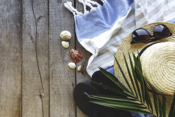 Concept of travel, vacation or weekends. Straw hat with palm leaf, shoes and eyeglasses, towel on wooden background. Relax time.