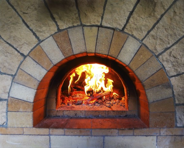 Burning firewood in traditional oven at restaurant kitchen