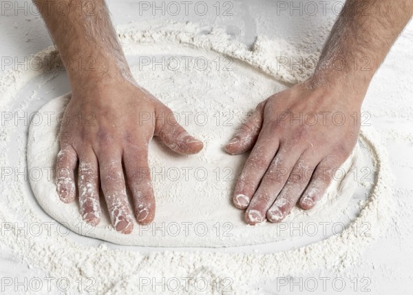 High angle man kneading pizza dough