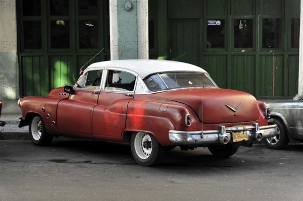 A red vintage car parked on a street corner in Cuba, Havana, Cuba, Central America