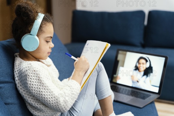 Side view little girl during online school with laptop headphones