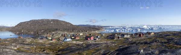 Rodebay, Greenland, July 09, 2018: Colorful wooden houses with icebergs in the background. Rodebay, also known as Oqaatsut is a fishing settlement north of Ilulissat, North America
