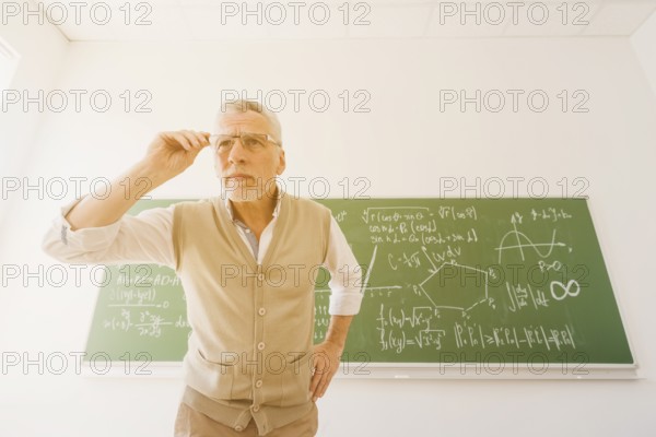 Aged professor looking through glasses classroom
