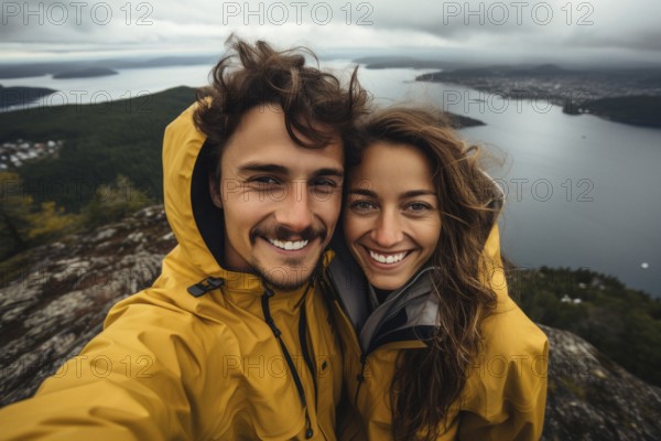 Young couple in mackintosh stands beaming with joy in free nature. behind Nordic landscape and forest, hiking, outdoor, selfie, happy, KI generated, AI generated