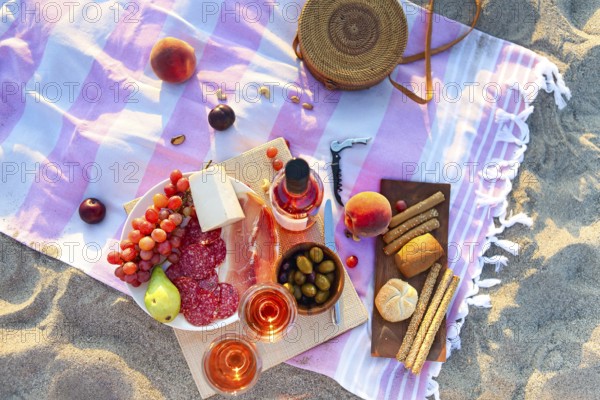 Picnic outdoor with rose wine fruits meat and cheese. Sunset