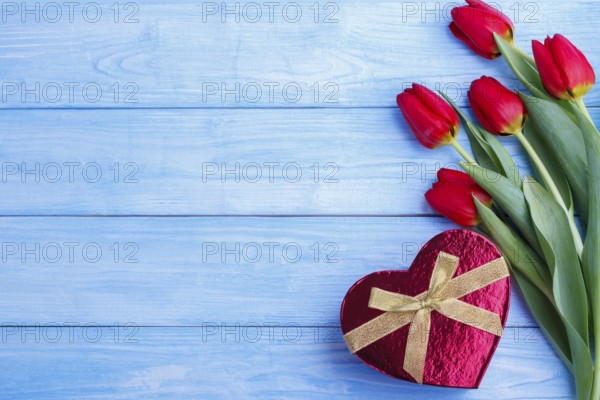 Bouquet of red tulips and gift box on rustic wooden board.copy space