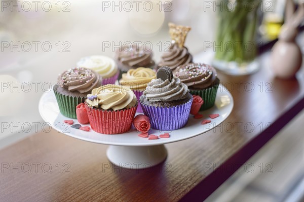 Eight deliciously sweet cupcakes covered with creamed chocolate, vanilla and various other garnishments alongside little pink heart candies