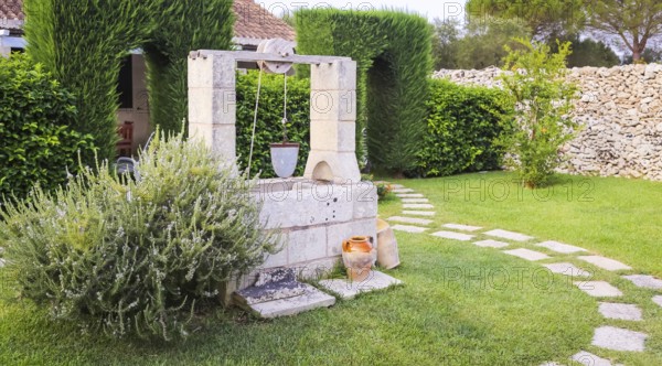 Summer season in Italy. Desing water well in an elegant garden