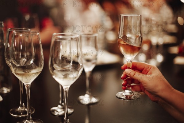 Glasses with different types of wine and human hands holding wine glasses in the background. Degustation wine
