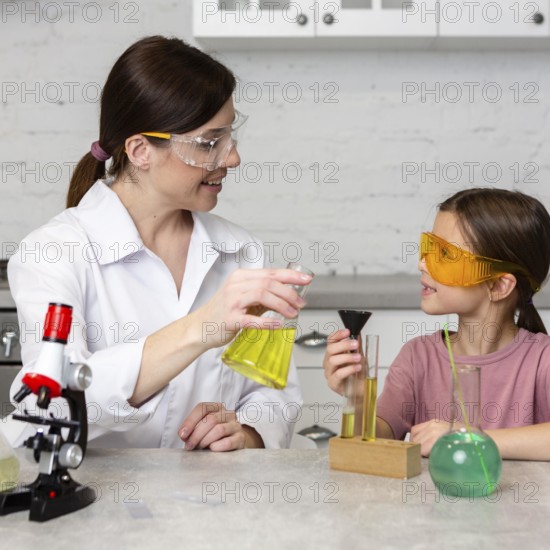 Little girl female teacher doing science experiments with test tubes
