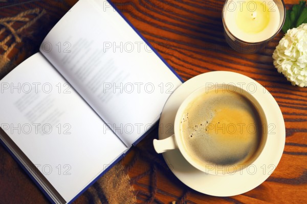 Coffee, book, plaid and candle at home. Food, hygge and comfort concept