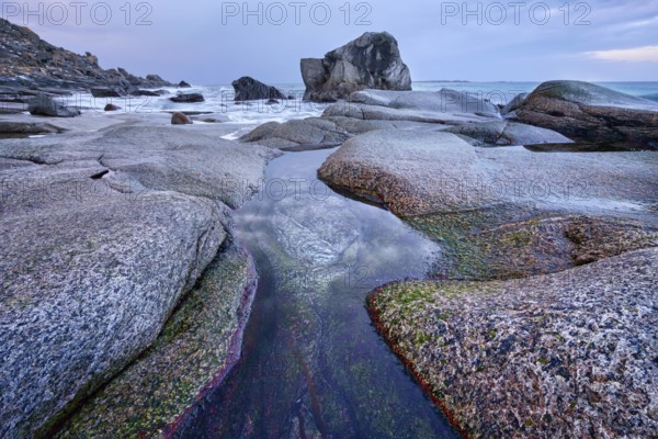 Rocks on beach of fjord of Norwegian sea in winteron sunset. Utakliev beach, Lofoten islands, Norway, Europe