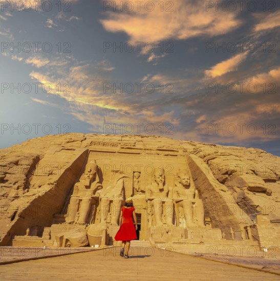 A European tourist in red dress walking towards the Abu Simbel Temple in southern Egypt in Nubia next to Lake Nasser. Temple of Pharaoh Ramses II, travel lifestyle
