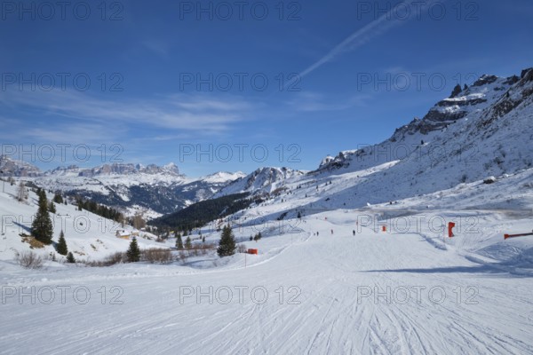 View of a ski resort piste with people skiing in Dolomites in Italy. Canazei, Italy, Europe