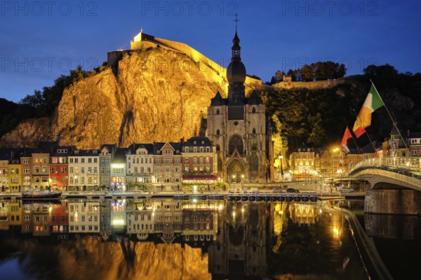 Night view of Dinant town, Collegiate Church of Notre Dame de Dinant over River Meuse and Pont Charles de Gaulle bridge and Dinant Citadel illuminated in the evening. Dinant, Belgium, Europe