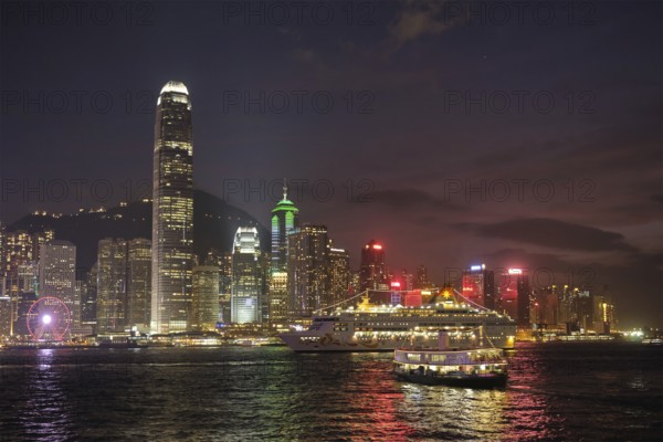 HONG KONG, CHINA, MAY 1, 2018: Hong Kong skyline cityscape downtown skyscrapers over Victoria Harbour in the evening illuminated with cruise ship. Hong Kong, China, Asia