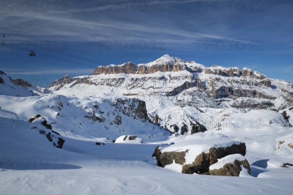 View of a ski resort piste with people skiing in Dolomites in Italy with cable car ski lift. Ski area Arabba. Arabba, Italy, Europe